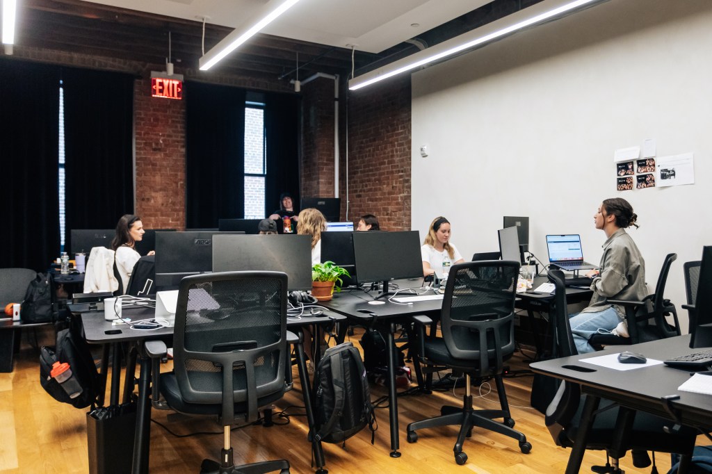 A group of people sitting at tables with computers in Bilt office, NoHo, Manhattan on June 6, 2024.