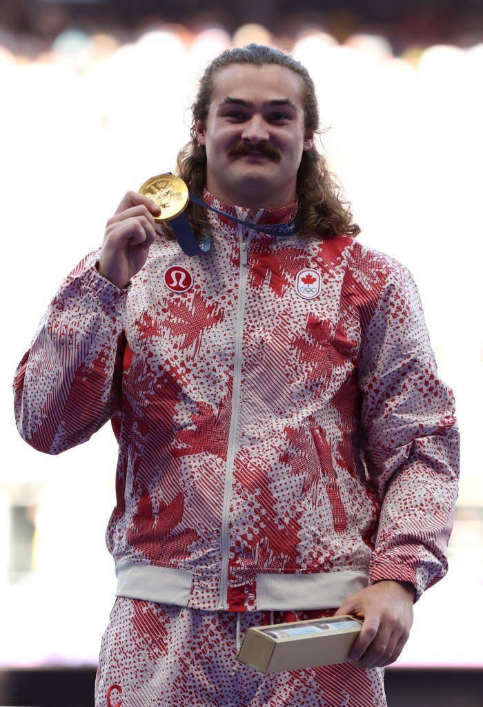 Gold medalist Ethan Katzberg of Team Canada celebrating on the podium after Men's Hammer Throw medal ceremony at the 2024 Paris Olympics