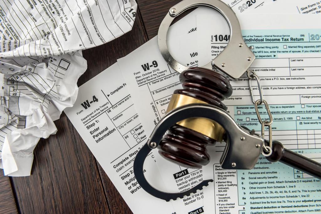 Handcuffs resting on top of tax papers and gavel 
