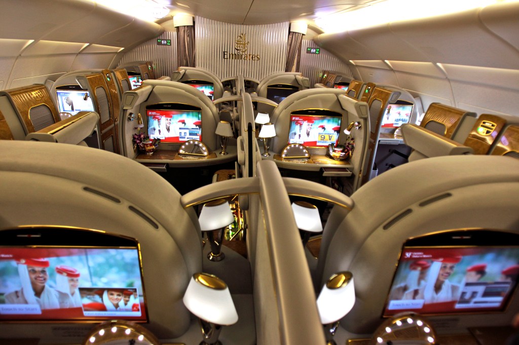 First class section of an Emirates Airlines Airbus A380, featuring a row of seats with computers on the back, ready for boarding at Dubai airport.