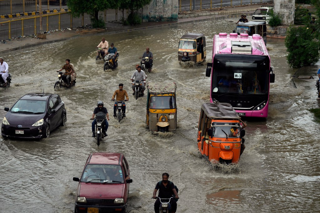 Motorcyclists and cars drive through a flooded road caused by heavy monsoon rainfall in Karachi, Pakistan, on July 30, 2024.