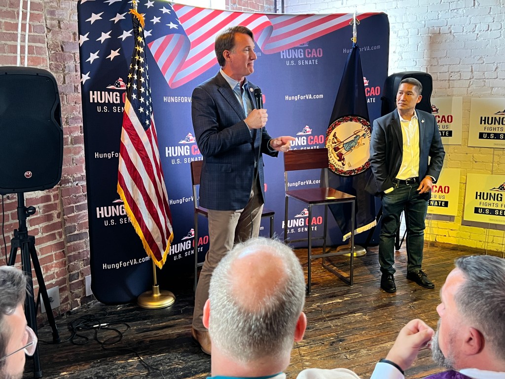 Governor Glenn Youngkin and VA GOP Sen. nominee Hung Cao at a campaign event, with one man standing on stage with a microphone