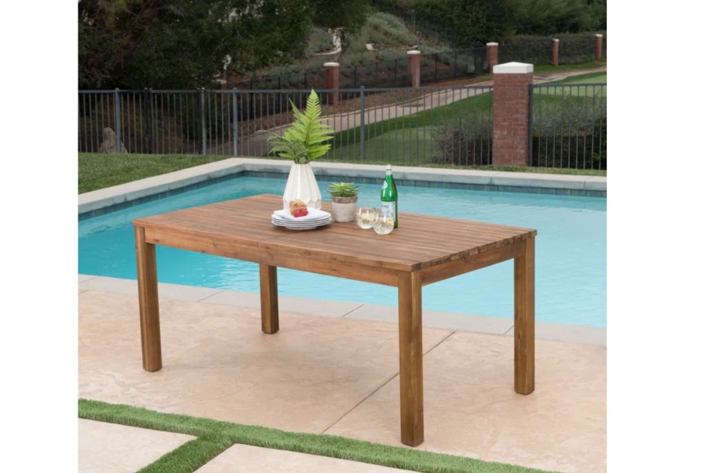 A wooden table in front of a pool.