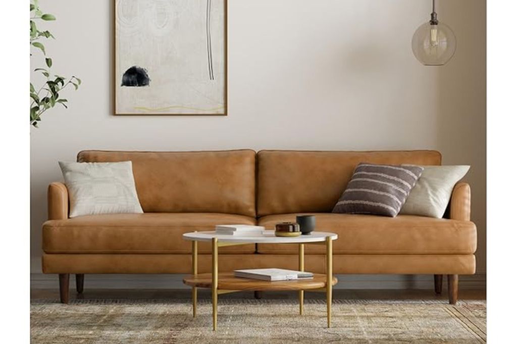 A brown leather couch with a coffee table in front of it.