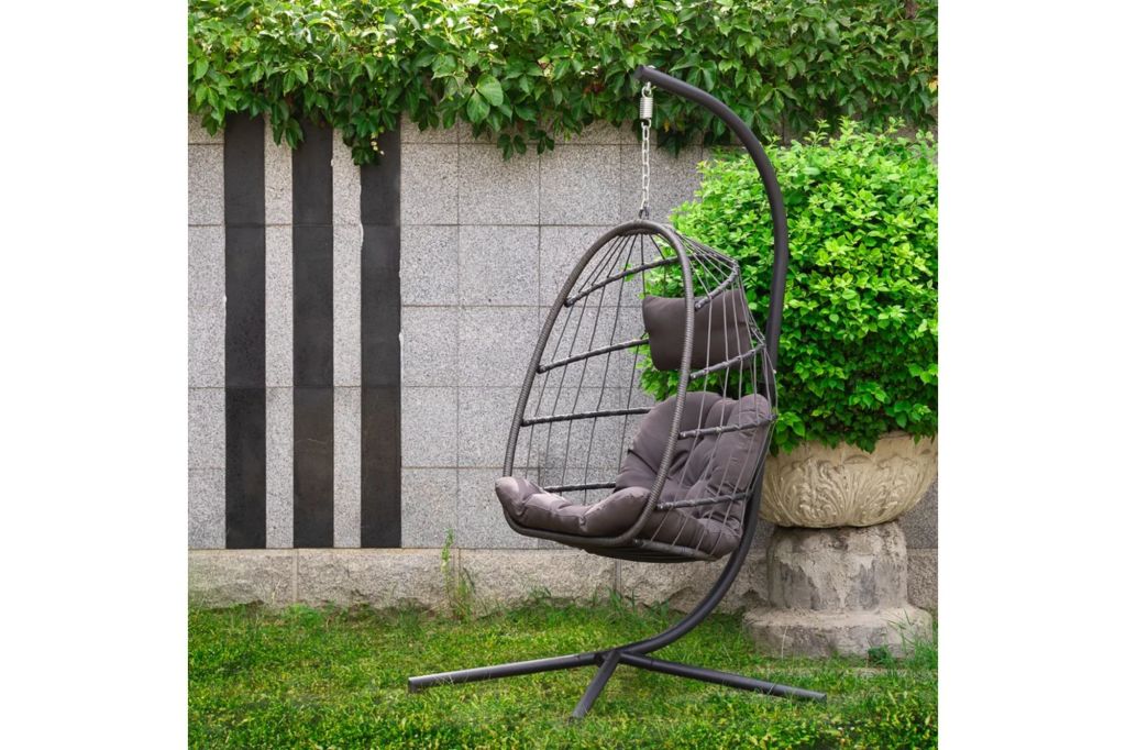 A egg shaped chair swing for the outdoors in a yard.