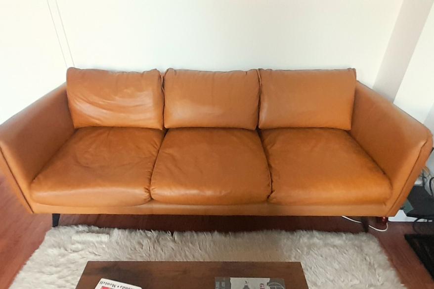 A brown leather sofa in front of a white shag carpet.