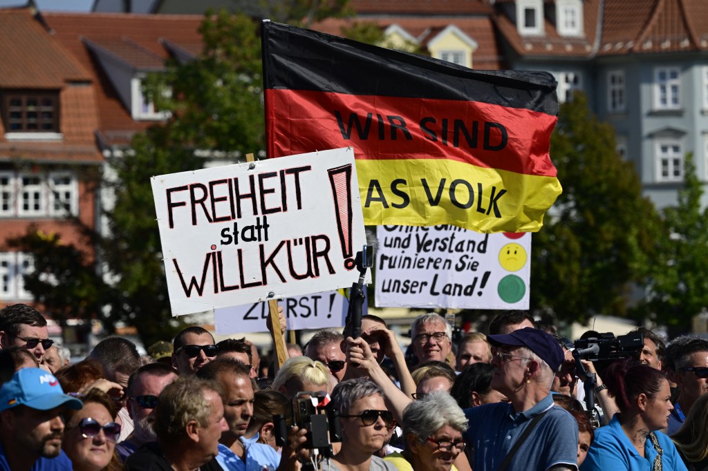 Supporters holding up the German national flag inscribed with 'We are the people' at a campaign event for the Alternative for Germany party in Erfurt, 2024