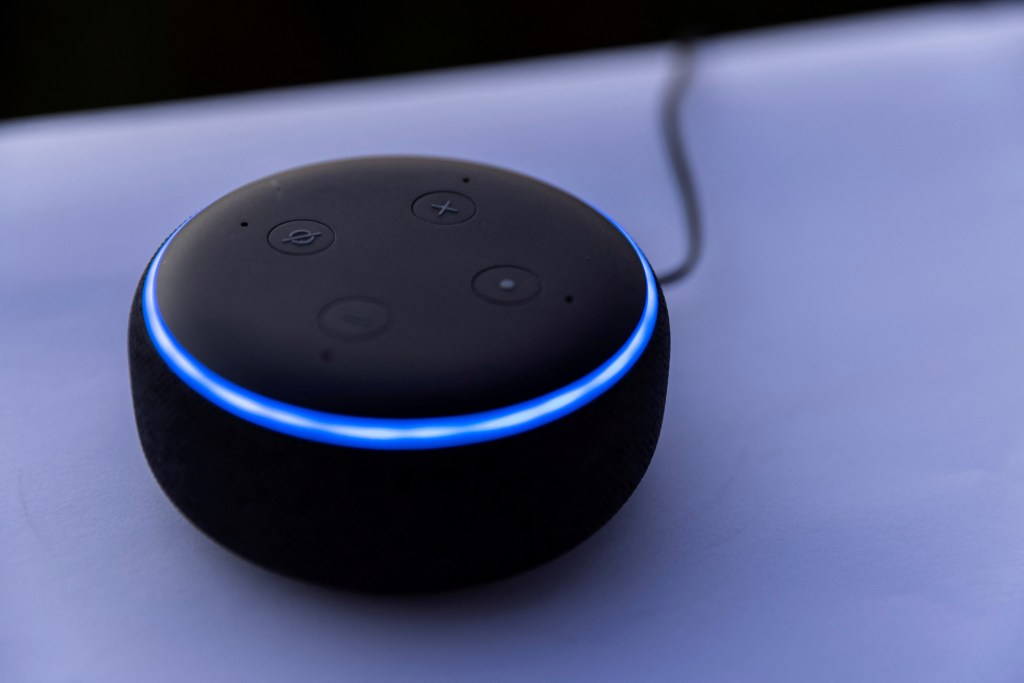 Amazon's DOT Alexa device, a round black device with a blue strip.