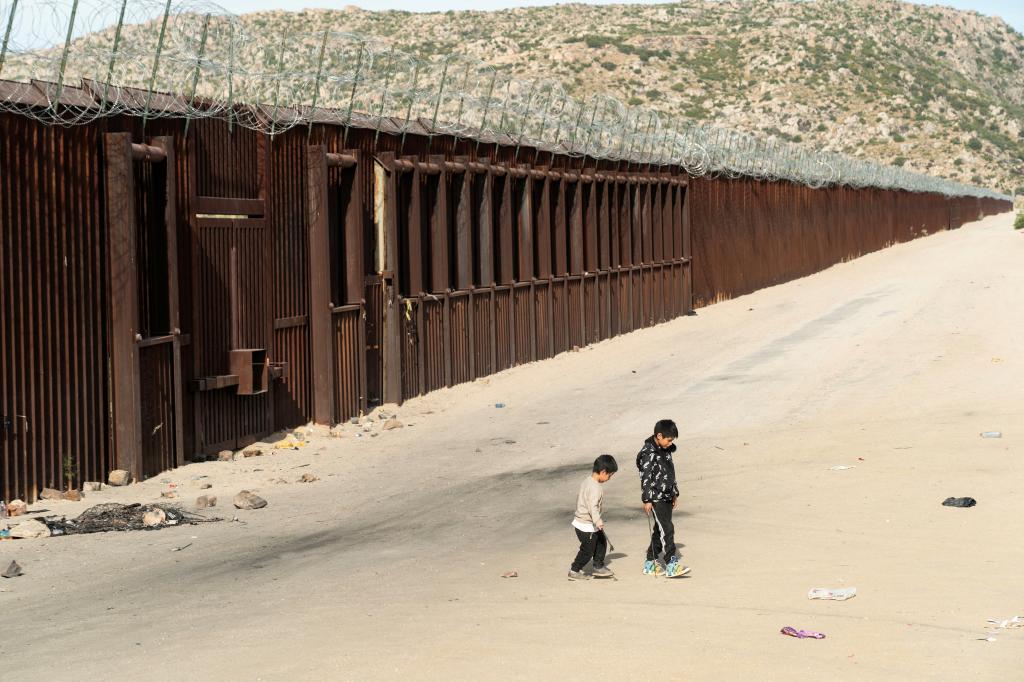 Asylum-seeking migrant children from Ecuador play near the border wall while waiting to be transported by the U.S. Border Patrol after crossing the border from Mexico into the U.S. in Jacumba Hot Springs, California, U.S. June 4, 2024.  