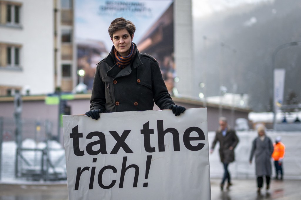 Person holding a sign that says "Tax the Rich"