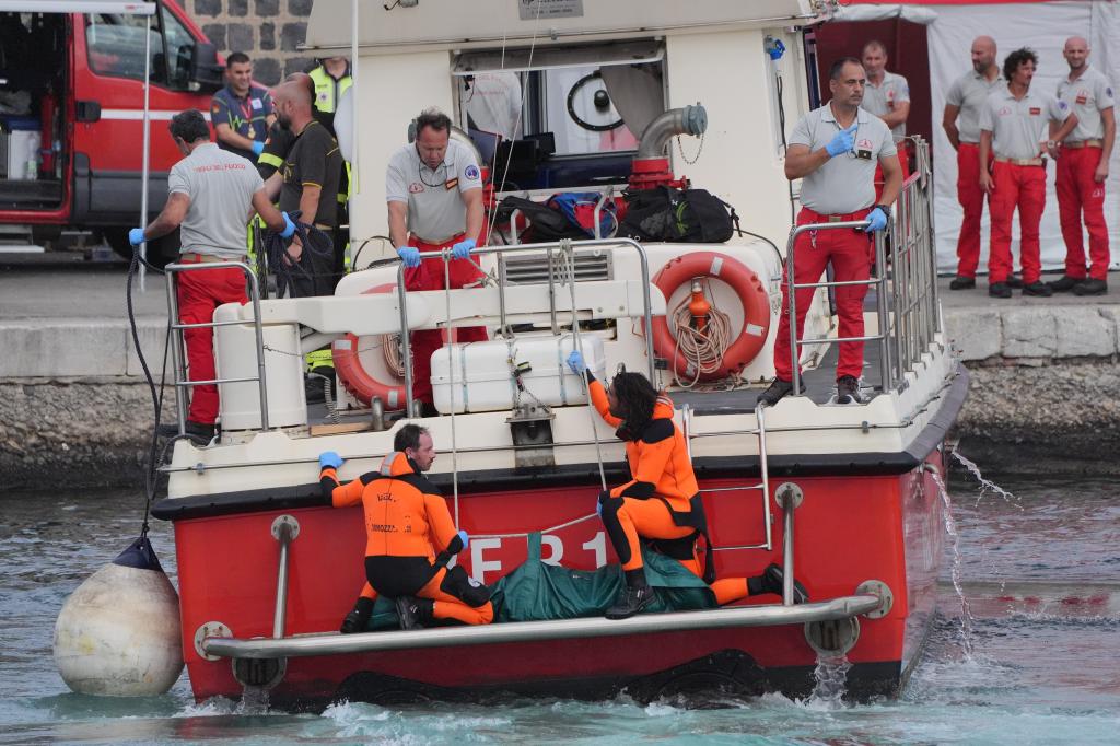 Rescue workers bringing a body bag ashore at Porticello harbour following the Bayesian yacht accident