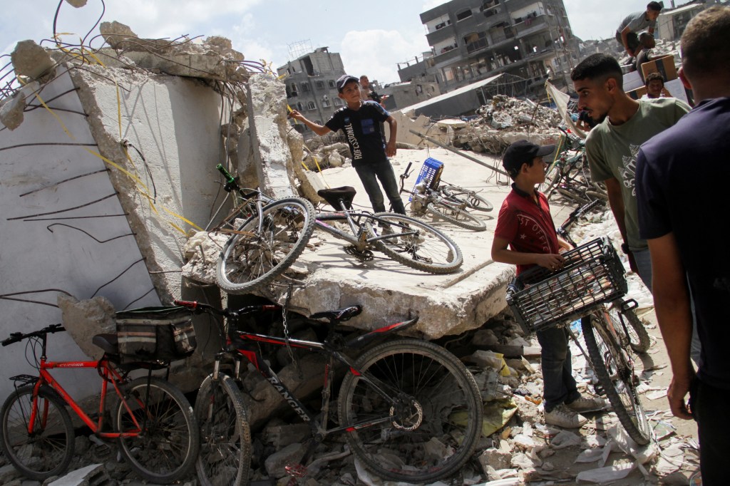 A boy stands on rubble as Palestinians gather to receive aid, including food supplies provided by World Food Program (WFP)