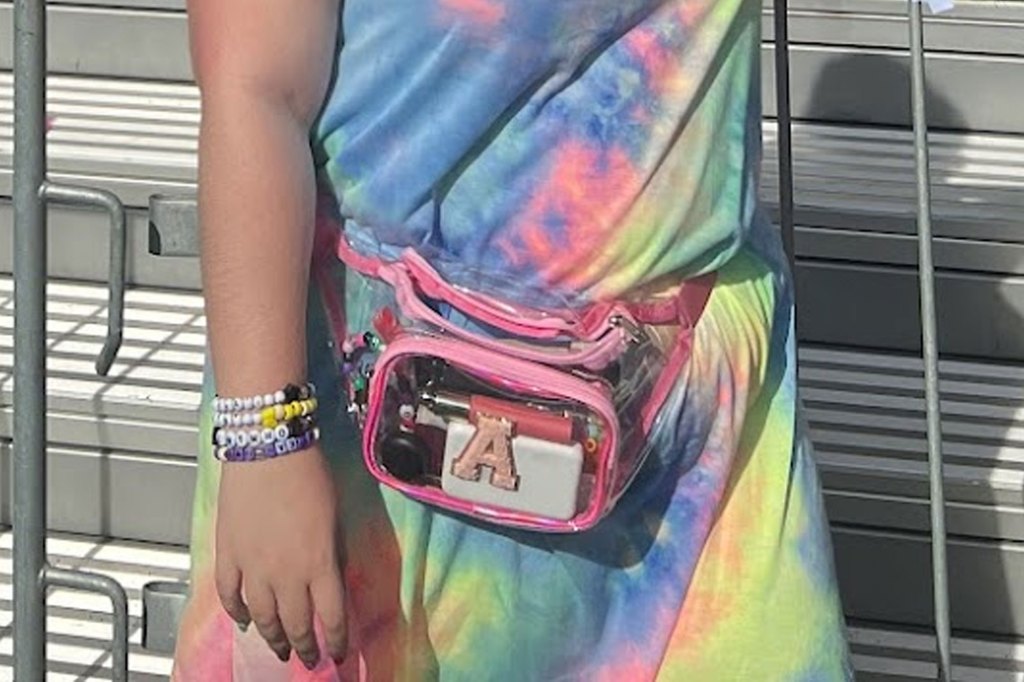 A person wearing a tie dye shirt and a clear belt bag