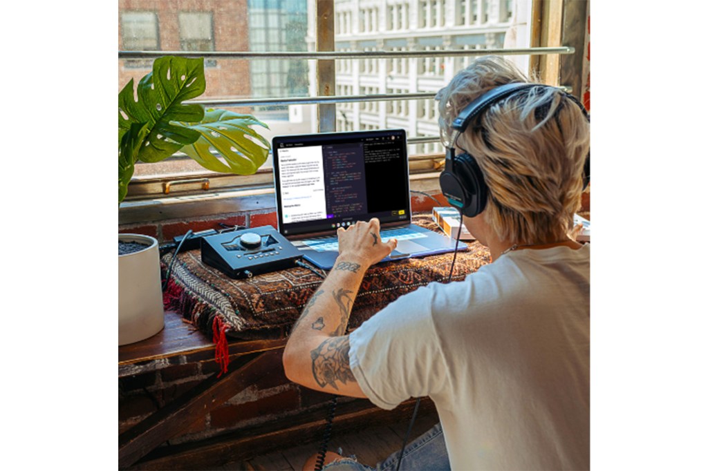 A person wearing headphones and using a laptop learning with Codecademy. 