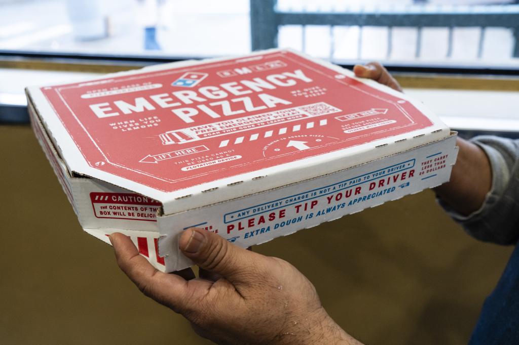 A customer holds a pizza box inside a Domino's Pizza restaurant in the Brooklyn borough of New York, US, on Wednesday, Jan. 24, 2024.