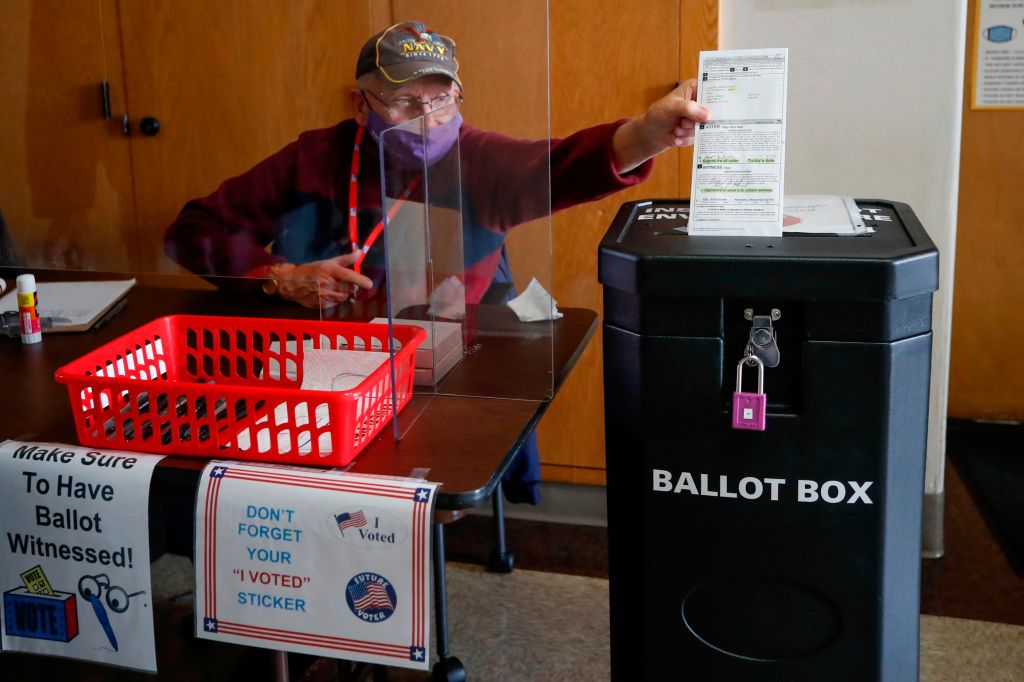 Election worker dropping a completed ballot into a ballot box during the first day of in-person early voting at City Hall in Kenosha, Wisconsin.