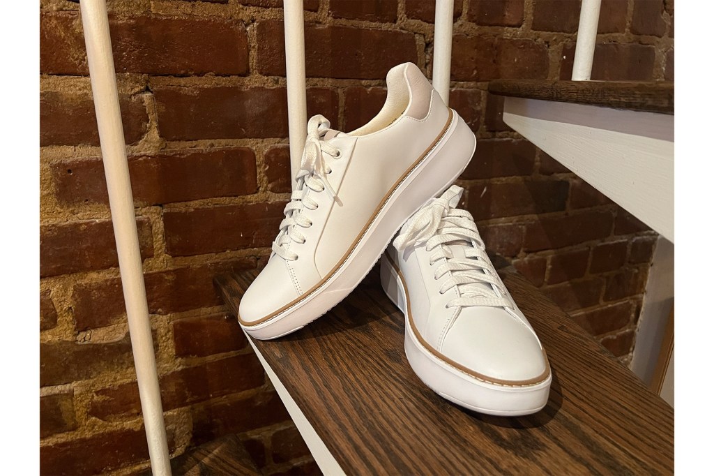 A pair of white shoes on a wooden stair. 