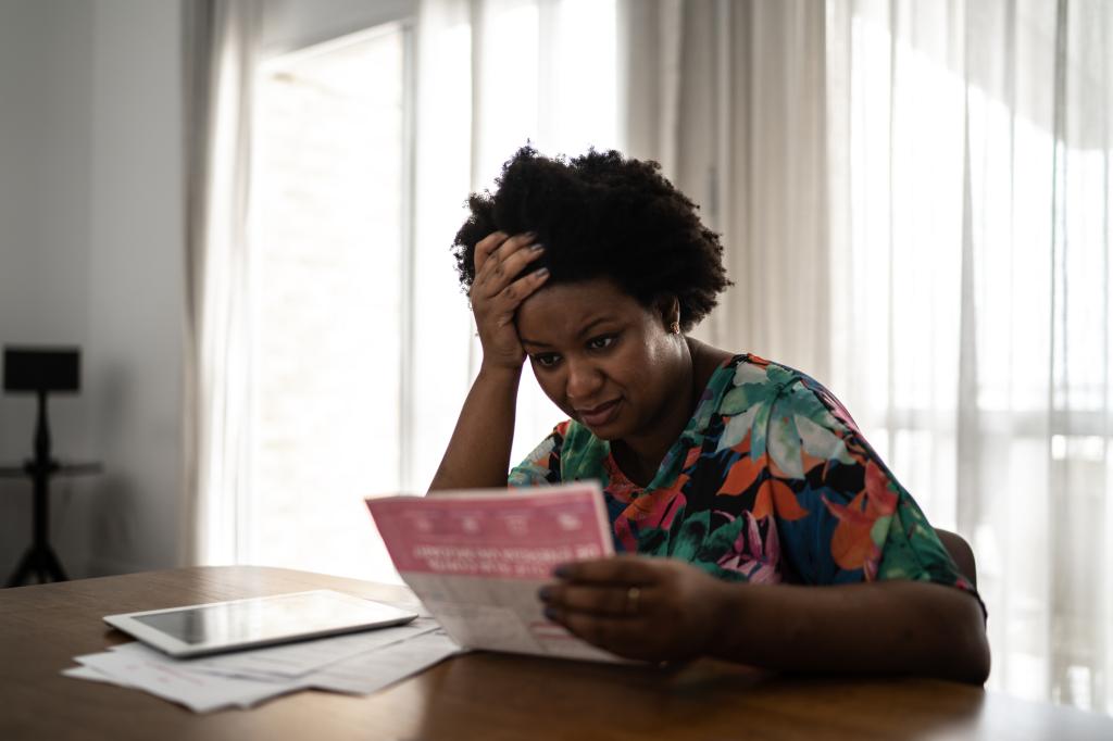 Worried woman holding her head while looking at a financial bill at home