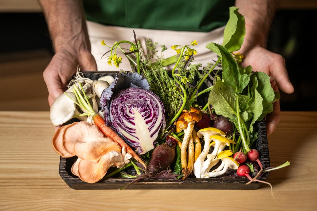 A person holding a tray of vegetables