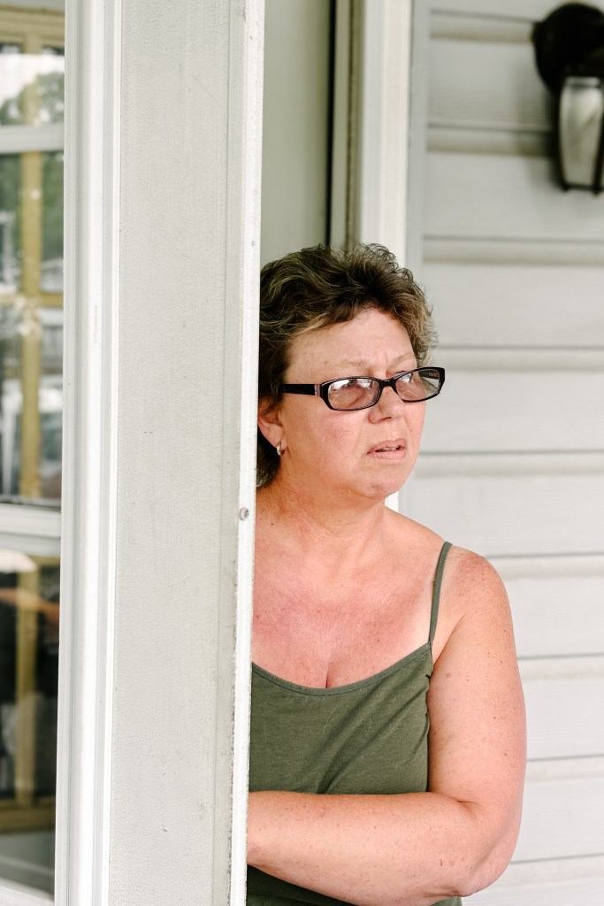 Lisa Jeanine Findley looking out the window on her porch in Kimberling City, MO on June 5th, 2024