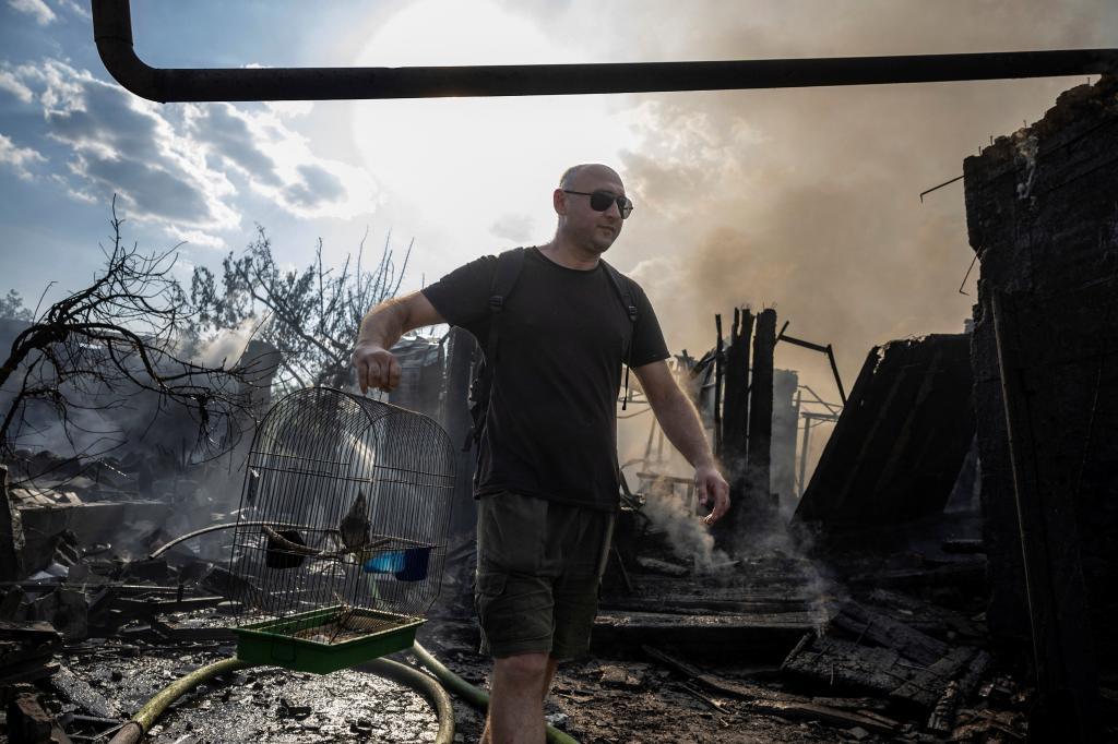 A Ukranian man carries a cage holding a pet bird from a house that was destroyed by a Russian strike on a residential area in Pokrovsk Saturday.