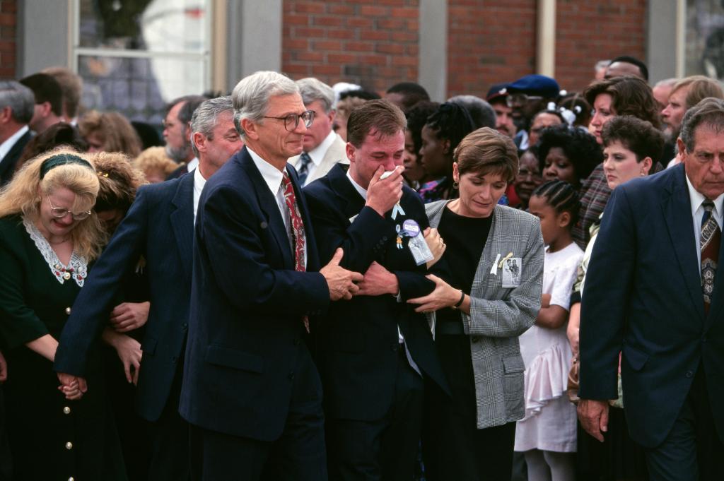 A picture of David Smith being comforted by relatives as he arrives for his sons' funerals.