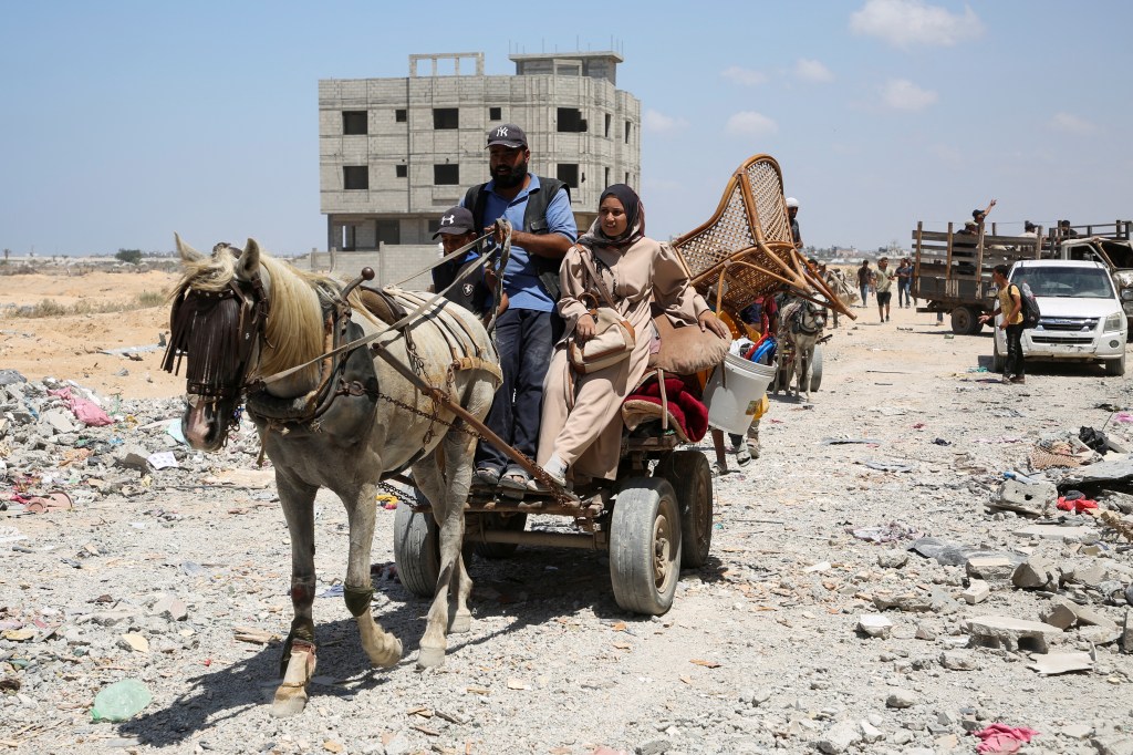 Palestinians ride an animal-drawn cart loaded with belongings in Qatari-funded Hamad City, following an Israeli raid.