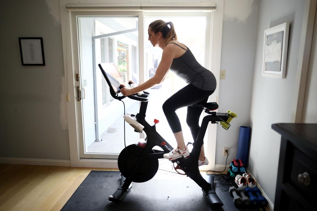 Woman, Jen Van Santvoord, exercising at home on her Peloton bike during the COVID-19 pandemic