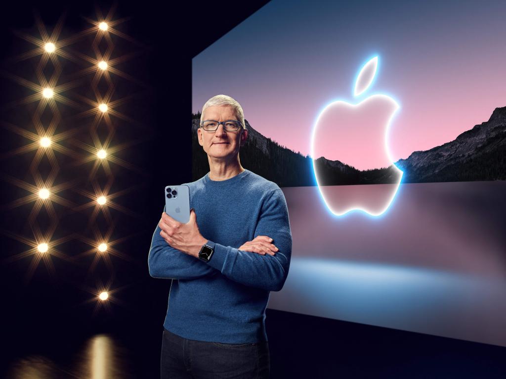 CEO Tim Cook holding iphone in front of apple logo