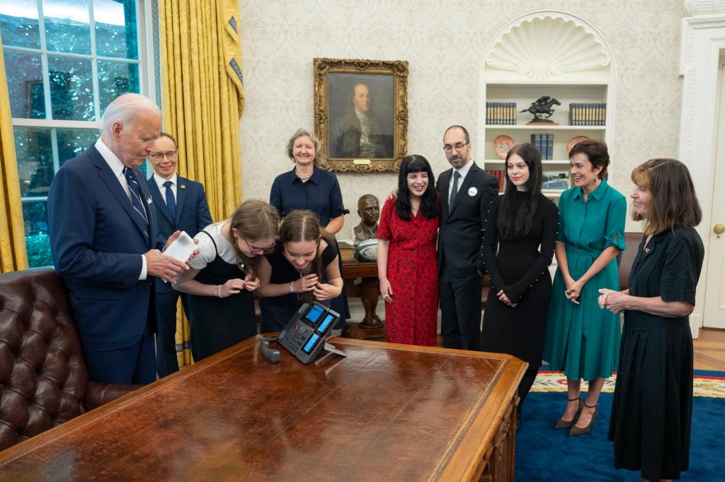 In this image released by the White House US President Joe Biden (L), with prisoners relatives, watches as sisters Miriam (3rd L) and Bibi Butorin speak with their mother, released prisoner journalist Alsu Kurmasheva, in the Oval Office of the White House in Washington DC, on August 1, 2024.