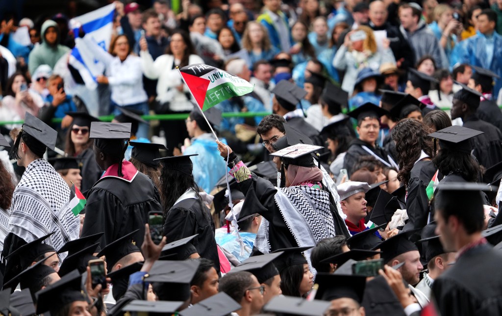 Pro-Palestinian protesters wearing keffiyeh and waving Palestinian flags at MIT's commencement ceremony