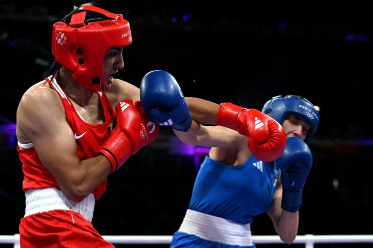 Algeria's Imane Khelif in red boxing gear, punching Italy's Angela Carini during a women's 66kg boxing match at the Paris 2024 Olympic Games