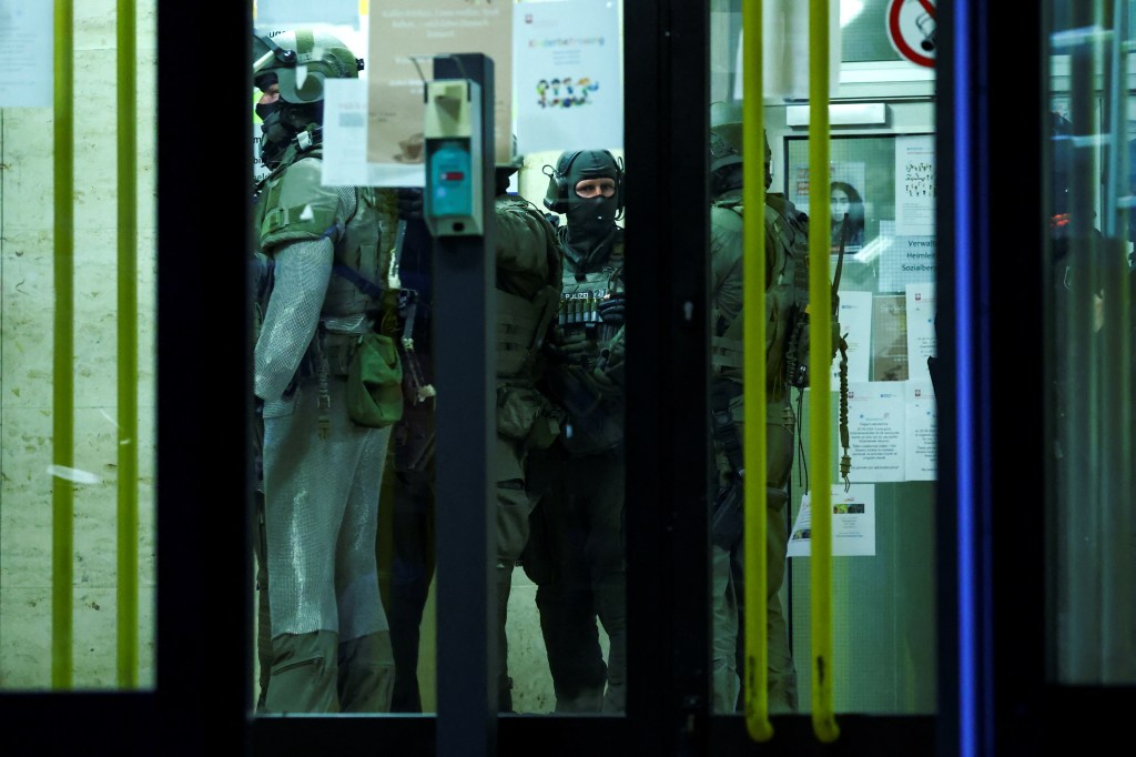 Special police forces officers stand inside of a building, following an incident in which several individuals were killed after a man randomly stabbed passers-by with a knife at a city festival.