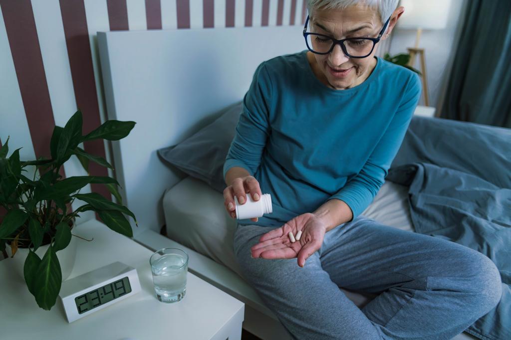 Mature woman taking a melatonin supplement pill before bed for promoting healthy sleep