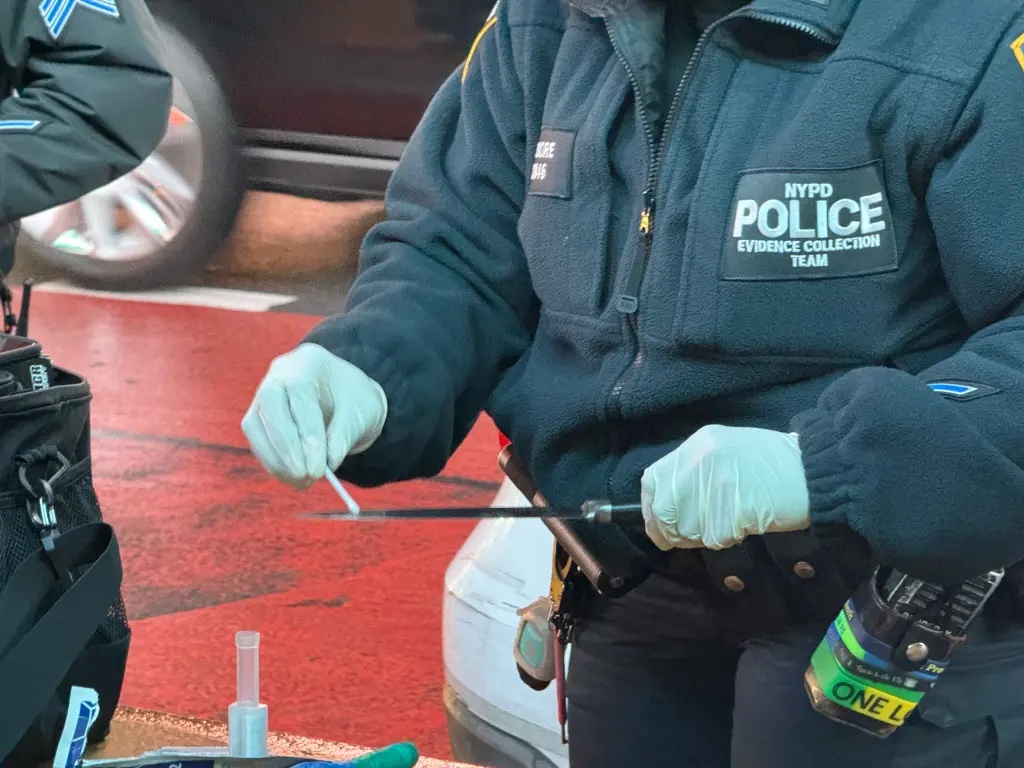 A photo of an NYPD cop collecting evidence off a knife.