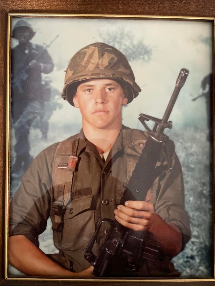 Tim Walz in a National Guard portrait, wearing his uniform and holding a rifle