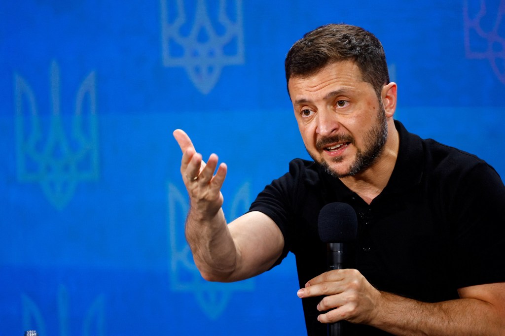 Ukraine's President Volodymyr Zelenskiy holding a microphone during a press conference in Kyiv, discussing the need for more F-16s from NATO nations