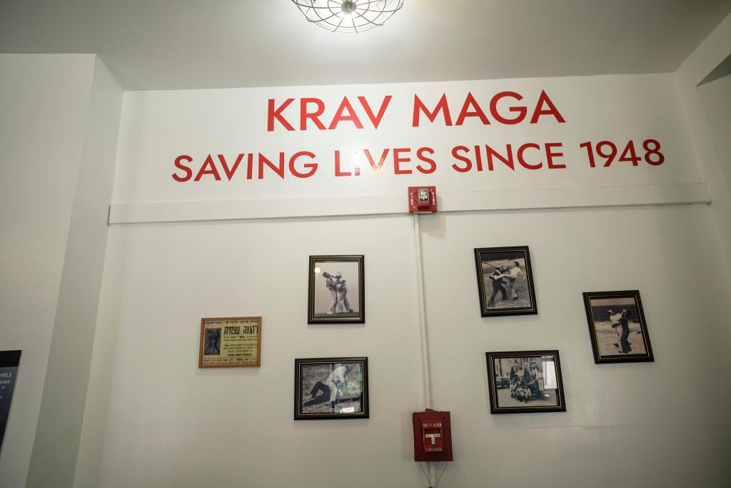 Wall with photos and the words "Krav Maga: Saving Lives Since 1948" at a Krav Maga story. 