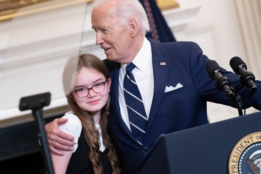 US President Joe Biden embraces Miriam Butorin, the 12-year-old daughter of Aslu Kurmasheva, as he speaks about the prisoner exchange with Russia, in the State Dining Room of the White House in Washington, DC, on August 1, 2024.