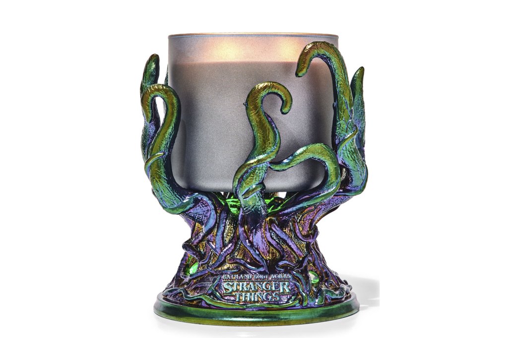 A candle holder with a vine design holding a candle