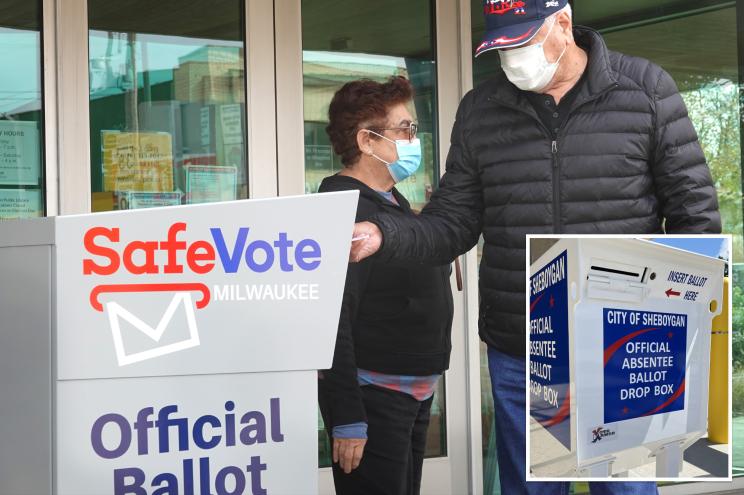 A man and woman wearing face masks in front of a sign saying 'TCS: Wisconsin communities say no to ballot drop boxes'