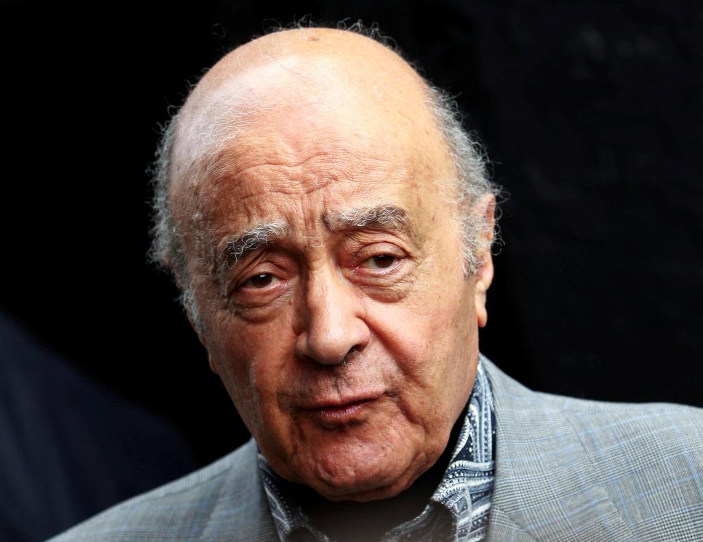 Mohamed Al-Fayed in a grey suit listening to Mark Hughes during a news conference at Craven Cottage stadium in London, August 3, 2010.