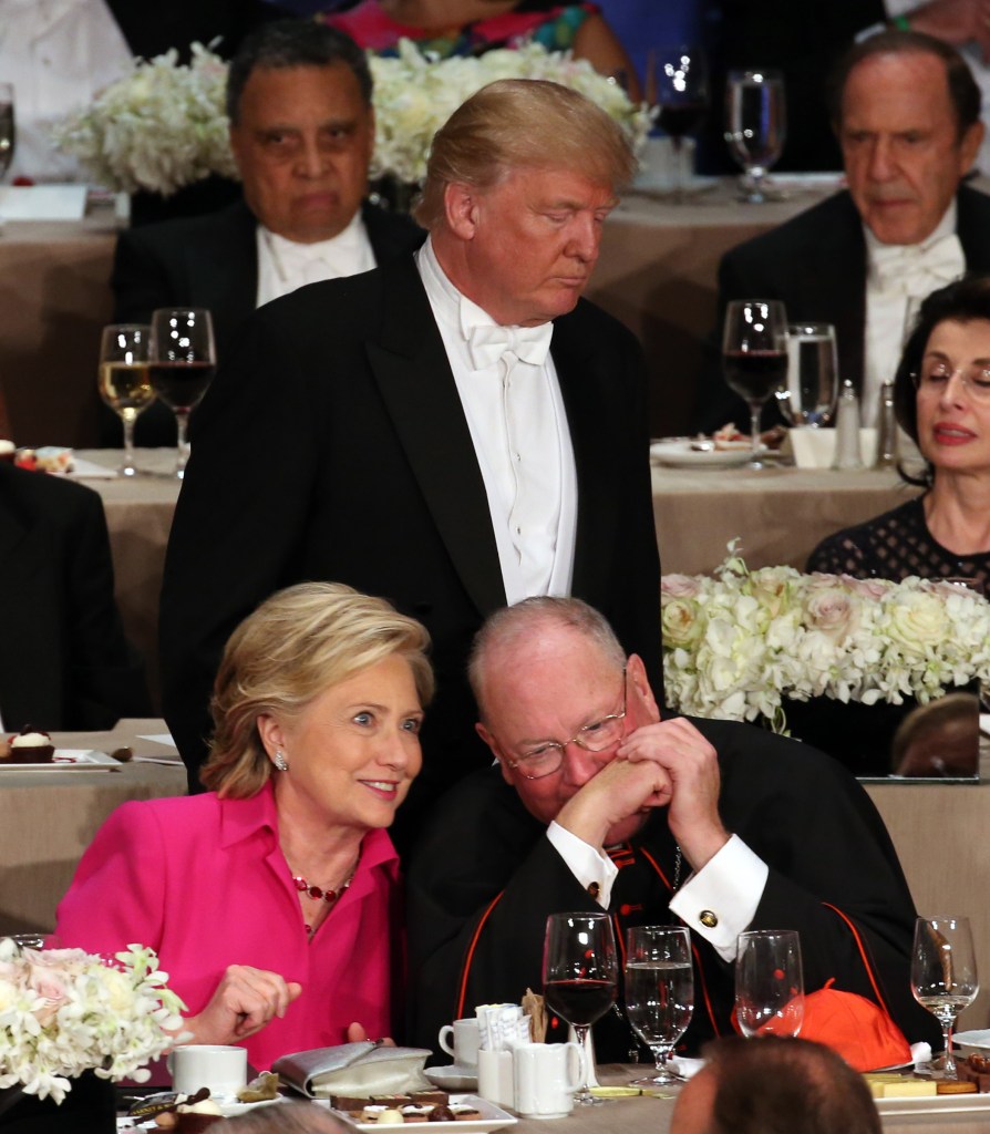 Donald Trump returning to his seat while Cardinal Timothy Dolan converses with Hillary Clinton at the 71st annual Alfred E. Smith Memorial Foundation Dinner in New York