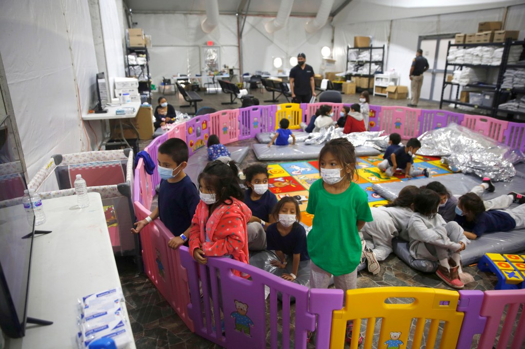 Unaccompanied migrant kids sit inside a playpen while in Border Patrol custody.