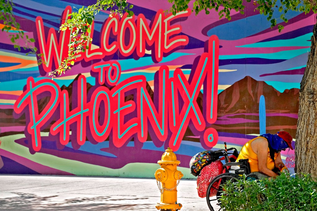 A homeless man sits under the shade of a tree, Thursday, July 13, 2023 in downtown Phoenix