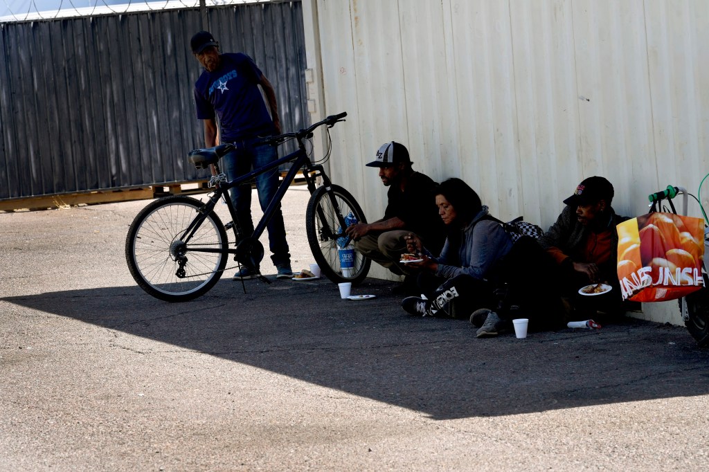 Homeless people sitting in the shade at a Phoenix soup kitchen on May 30, 2024.