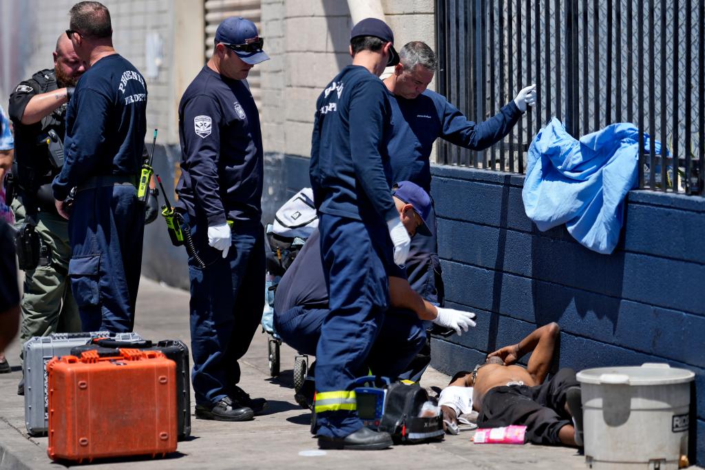 Phoenix firefighters giving medical attention to a homeless man on a hot sidewalk on May 30, 2024.