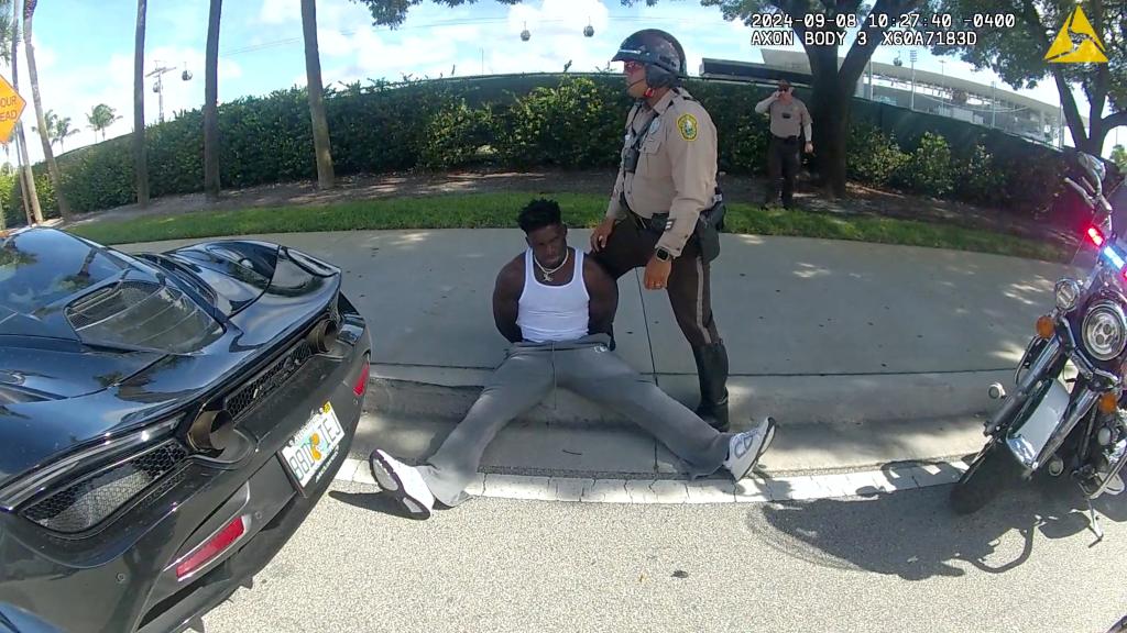 Miami Dolphins receiver Tyreek Hill sits handcuffed on the sidewalk during a traffic stop, in Miami Gardens, Florida, U.S., September 8, 2024.