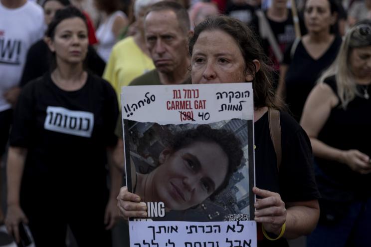 A protester holds a photo of slain hostage Carmel Gat