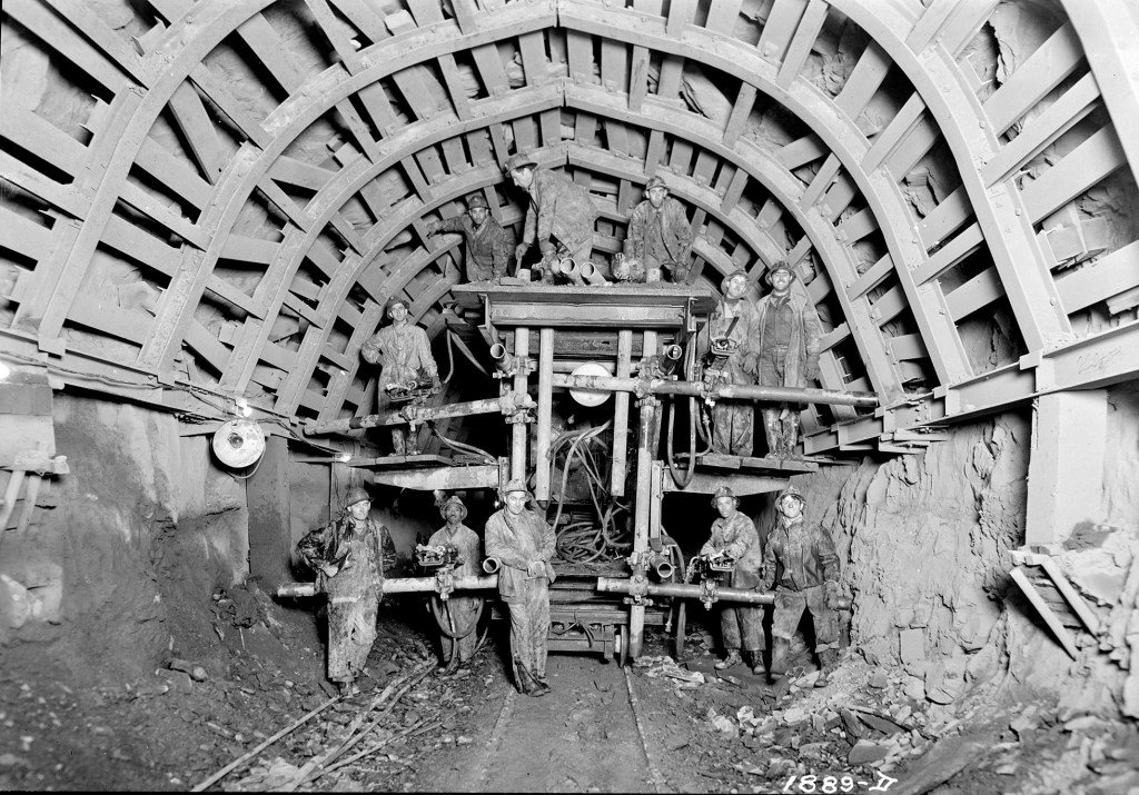 Men working on Delaware Aqueduct with drill carriage equipped for harmful dust removal, in tunnel under construction, circa 1939.